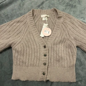 Beige stickad kofta från Odd Molly - Superfin vintage beige stickad kofta från Odd Molly med ribbat mönster, v-ringning och knappar framtill. Kortare modell med mjukt material och trekvartsärm. Perfekt för lager-på-lager och snygg till både jeans och kjol.