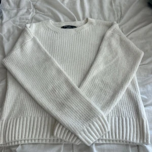 Vit ribbstickad tröja FB Sister - Säljer en vit ribbstickad tröja från FB Sister i storlek XXS men är även som storlek S. Tröjan har rund halsringning, långa ärmar och är gjord i mjuk polyester. Perfekt för lager på lager under kyliga dagar. Enkel och stilren design som passar till det mesta.