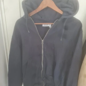 Mörkblå hoodie med dragkedja från Weekday - Säljer en mörkblå hoodie från Weekday med huva och hel dragkedja framtill. Tröjan har känguruficka och långa ärmar, perfekt för en chill och avslappnad stil. Klassisk modell som funkar året runt.