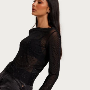 Svart mesh topp med glittriga detaljer - Säljer en svart mesh topp med lång ärm och glittriga små stenar över hela tyget. Toppen är lätt genomskinlig, perfekt för festliga tillfällen 😊 Använd fåtal gånger 
