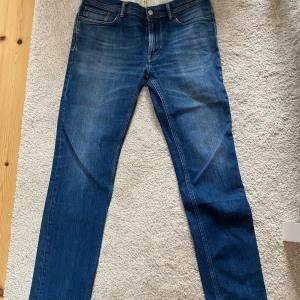 Herr jeans från Acne Studios - Snygga blå jeans från Acne Studios i klassisk modell med raka ben och fem fickor. Jeansen är i mörkblå tvätt. Materialet är bomull med lite stretch för extra komfort. Storlek 34/32 passar runt 180cm. Skriv för fler bilder. Nypris 4000kr mitt pris 1000kr