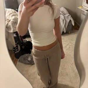 Vit och mörkgrå croppad topp med öppen rygg - Två croppade toppar i vitt och mörkgrå med kort ärm och djup öppen rygg. Snygg, tight passform som framhäver figuren. Perfekt till jeans eller kjol för en trendig look. Mjukt och stretchigt material som sitter skönt hela dagen.