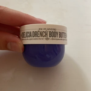 Sol de Janeiro Delicia Drench Body Butter - Delicia Drench Body Butter från Sol de Janeiro i en snygg lila rund burk med vit lock. Doft av Cheirosa 59, innehåller prebiotisk hibiskus och Brazilian Soothing Complex. Perfekt för dig som älskar återfuktande och lyxiga kroppskrämer.