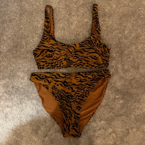 Brun och svart bikini med zebramönster - Snygg bikini i brunt och svart med zebramönster. Överdelen har breda axelband och sportig form, medan underdelen är högt skuren för en trendig look. Perfekt för stranden eller poolen. 