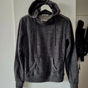 Mörkgrå hoodie från Alexander Wang - Snygg mörkgrå hoodie från Alexander Wang med huva och snörning. Tröjan har en känguruficka framtill och synliga sömmar som ger en cool look. Perfekt för dig som gillar streetwear och vill ha något stilrent men ändå unikt.