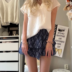 Blå volangkjol från Meet x Tiger - Supersöt blå kortkjol med  mönster från Meet x Tiger. Kjolen har volanger och resår i midjan. Kjolen har även shorts inuti 💓💓. Storlek xxs/xs. Längden på kjolen går att bestämma själv beroende på om man bär den som low, mid eller hög midja 
