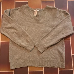 Grå v-ringad ulltröja - Mysig grå v-ringad tröja i ull från NSN. Klassisk modell med ribbade muddar vid ärmslut och nederkant. Perfekt för lager-på-lager och passar till allt. Långärmad och enkel att styla till både jeans och kjol.