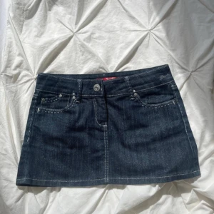 Jeanskjol - Mörkblå jeanskjol med vita stygn. Inga tecken på användning. MIDJEMÅTT: 39 cm, LÄNGD: 30 cm