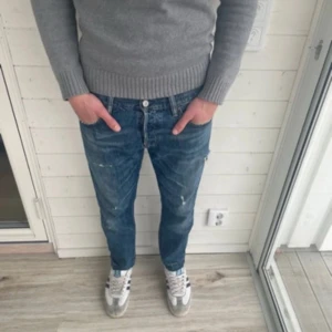 Blå jeans från Denim & Supply Ralph Lauren - Säljer ett par blå jeans från Denim & Supply Ralph Lauren med slitna detaljer och snygg tvätt. Jeansen har klassisk femficksdesign, normal passform och raka ben. Märkespatch bak i midjan och coola slitningar för en avslappnad look.