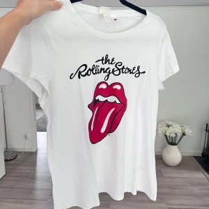 Rolling Stones t-shirt - Vit t-shirt med klassiskt Rolling Stones-tryck framtill. T-shirten har rund hals, korta ärmar och är gjord i mjuk bomull. Perfekt för dig som gillar bandmerch. Önskar du veta exakta mått? Tveka inte att höra av dig! 🤍❤️