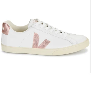 Vita Veja sneakers med roséguld-detaljer - (OBS) Är inte hemma just nu, men om du frågar om bilder skickar jag, när jag kommit hem! Dom är väll använda!!!Snygga vita sneakers från Veja med roséguldfärgad logga och häl. Skorna har klassisk låg profil, snörning och är tillverkade i skinn. Perfekta för dig som vill ha en clean look med en touch av metallic. 