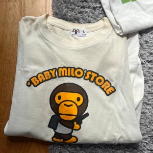 Vintage Baby Milo Store t-shirt i vitt - Otroligt ovanlig och vacker vintage baby milo T-shirt från bape🐒. Runtomkring 20 år gammal och använd otroligt sparsamt. Otroligt hög kvalité som det brukar vara på japanska kläder. Eftersom den är direkt från Japan så är den liten i storleken, passar medium 🦧pris går såklart att diskutera vid smidiga affärer