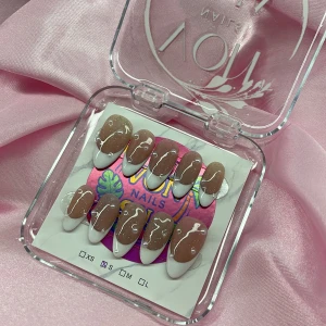 SugarDew (S);Medium Almond - Snygga gelé press-on naglar i storlek S: 15 mm, 11,5 mm, 12 mm, 11 mm, 9 mm. Naglarna har en nude bas med superglitter, vit fransk tipp och vita swirl-detaljer. Perfekt för dig som vill ha trendiga naglar snabbt!