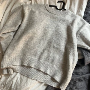 Ljusgrå stickad tröja Gina Tricot - Supermjuk ljusgrå stickad tröja från Gina Tricot med rund halsringning och ribbade muddar. Perfekt för lager-på-lager och kallare dagar. Säljer eftersom den inte kommer tillanvändning. 