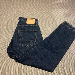 Mörkblå jeans från Jack & Jones - Snygga mörkblå jeans från Jack & Jones med raka ben. Jeansen har normal passform, femficksdesign och är tillverkade i robust denim. Perfekta för dig som gillar en avslappnad och trendig look.