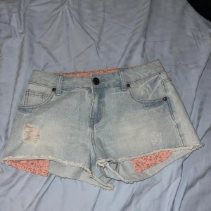 lågmidjade Ljusblå jeansshorts med rosa detaljer - Jätte gulliga y2k ljusblå jeansshorts, med låg midja och rosa detaljer som fickorna som sticker ut och det rosa midjebandet. Med en distressed ficka. Säljer pga att de var för små för mig så kommer tyvärr inte skicka bilder med shortsen på💕 Kunde inte tyda märket men de är väldigt sommriga och gulliga.