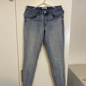 Ljusblå skinny jeans från Primark - Säljer ett par ljusblå skinny jeans från Primark med klassisk femficksdesign och gul kontrastsöm. Jeansen har normal midja och är tillverkade i stretchig denim för en tight passform. Perfekta till sneakers eller boots.