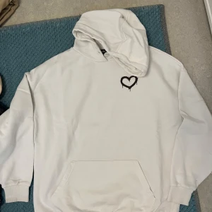 Vit hoodie med nalle och hjärta XS - Vit hoodie från Sister i storlek XS men oversize, med mörkbrun hjärta på bröstet och stor print på ryggen.