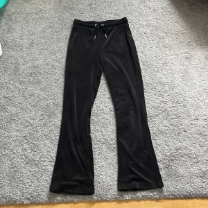 Svarta mjukisbyxor från Gina Tricot - Svarta mjukisbyxor från Gina Tricot i mjukt och glansigt material. Byxorna har bootcut-ben, dragsko i midjan och två bakfickor. Perfekta för en chill och avslappnad stil. 