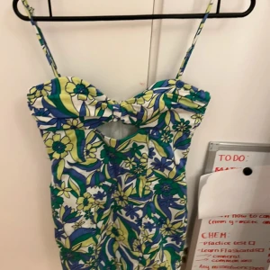 Blommig kortklänning från Zara - Superfin kort klänning från Zara med blommigt mönster i blått, grönt och gult. Klänningen har smala axelband, cut-out detalj framtill och dragkedja i sidan. Perfekt för sommarens alla tillfällen och ger riktiga retrovibbar!