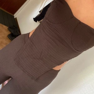 Brun axelbandslös två del sett  - Säljer en brun, axelbandslös två del sett sydd i ett stretchigt material som sitter snyggt på kroppen.