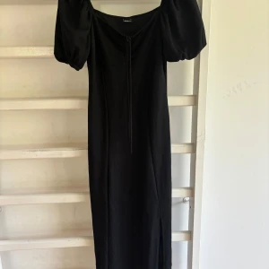 långklänning puffärmar - Svart långklänning från Gina Tricot med puffiga korta ärmar och snörning framtill. Aldrig använd!! 