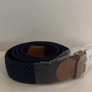 Mörkblått flätat bälte - Detta bälte är känt för sin klassiska mörkblåa färg som passar till det mesta. Det kan är elastiskt samt bra kvalitet på bältet så det håller länge och får en bättre passform. 