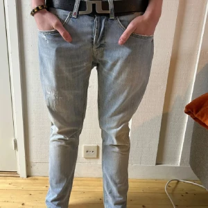Dondup George  - Säljer ett par ljusblå jeans i slim fit med snygga slitningar och klassiska fem fickor. Jeansen har normal midja och är tillverkade i mjukt denimtyg. Perfekta för dig som gillar en clean och avslappnad look.