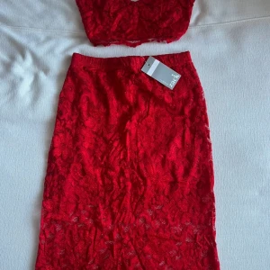 Röd spetsig croppad linnetopp med kjol - Säljer ett romantisk röd set från John Zack. Perfekt för dig som vill sticka ut med en färgstark och feminin look.