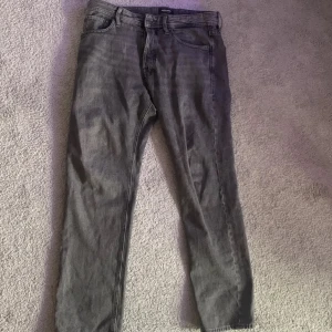 Grå jeans Relaxed/Chris Jack & Jones - Og pris: 600kr Säljs för: 259kr                                  Säljer ett par grå jeans från Jack & Jones som ja köpt för 3 dagar sedan och bara användt två gånger modellen är Relaxed/Chris. Jeansen har en avslappnad passform med raka ben och klassiska fem fickor. Tillverkade i denim med bälteshällor och dragkedjegylf. Perfekta för en chill och stilren look.