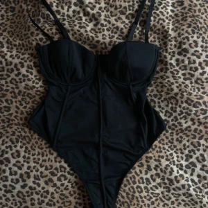 Svart korsettbody från NLY Lingerie - Säljer en svart korsettbody från NLY Lingerie med smala axelband och markerade kupor. Snygg, figurnära passform och stilrena sömmar som ger en cool siluett. Perfekt att styla med jeans eller kjol för en edgy look.