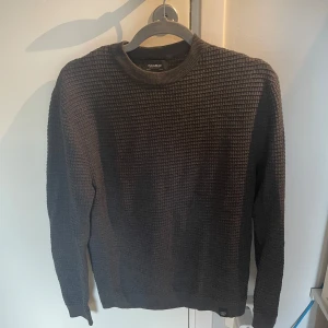 Mörkgrå stickad tröja Pull&Bear XS - Säljer en mörkgrå stickad tröja från Pull&Bear i storlek XS. Tröjan har ett snyggt rutigt strukturmönster och rund halsringning. Perfekt för lager-på-lager och chill höst- eller vinterstil. Långärmad och riktigt skön att bära.