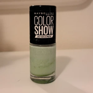 Maybelline Color Show Green With Envy - Nagellack från Maybelline Color Show i nyansen 214 Green With Envy. Färgen är en ljus pastellgrön med krämig finish. Kommer i en rund glasflaska med svart lock och rymmer 7 ml. Perfekt för dig som vill ha en unik och fräsch färg på naglarna.