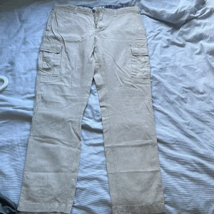 Beiga cargopants från Dressmann - Beiga cargopants från Dressmann med raka ben och klassiska cargofickor på sidorna. Storlek 36-32