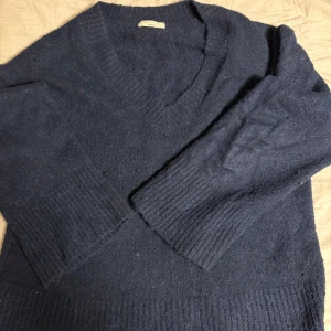 Mörkblå stickad v-ringad tröja - Mysig mörkblå stickad tröja från Gina tricot med v-ringning och breda ribbade muddar vid ärmslut och nederkant. Perfekt för lager-på-lager och chill höst- eller vinterstil. Klassisk modell med lång ärm och relaxed fit.