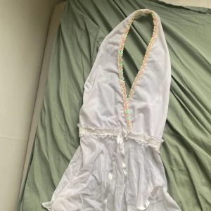 Vit topp med paljetter - Supersöt vit blus med djup v-ringning och glittriga paljetter längs kanten. Tunnt material och väldigt luftig. Söt med en liten rosett. 2000 och y2k vibes