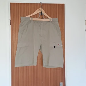 Beige cargoshorts från Everest - Snygga beige cargoshorts från Everest med flera praktiska fickor på sidorna. Klassisk passform med bälteshällor och diskret logga på benet. Perfekta för sommardagar eller utomhusaktiviteter. Lätta och bekväma i material som andas.