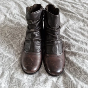 Bruna skinnboots från Tamaris - Snygga bruna boots från Tamaris i skinn med rund tå och låg klack. Skorna har dekorativt spänne i silver på sidan och dragkedja för enkel påtagning. Mjukt rynkat skaft och robust sula med bra grepp. Perfekta för höst och vinter! Köpta på sellpy för 60kr säljer för 30kr💞