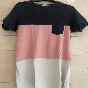 Blockfärgad t-shirt från Strömberg - T-shirt i ekologisk bomull från Strömberg med blockfärger i mörkblått, ljusrosa och beige. Bröstficka framtill och liten broderad detalj längst ner. Klassisk passform och korta ärmar, perfekt för en chill look.