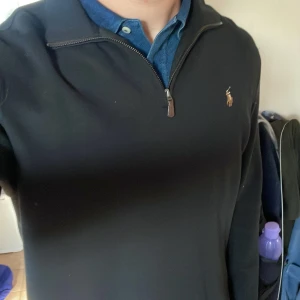 Svart långärmad tröja med dragkedja från Polo Ralph Lauren - Tjena, Säljer en svart långärmad tröja från Polo Ralph Lauren i storlek M. Tröjan har halv dragkedja vid halsen och den klassiska broderade loggan på bröstet. Perfekt för en stilren och avslappnad look.passar som en större M , köpt på hede fashion outlet i Kungsbacka vinter 23-24. Använd fåtal gånger
