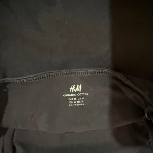 Svart bomullströja från H&M, M - En basic svart tröja från H&M i ekologisk bomull. Enkel och stilren modell med rund hals och normal passform. Perfekt att matcha med jeans eller kjol för en clean look. Storlek M.