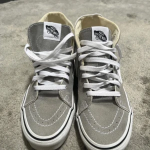Gråa vans sneakers - Snygga vans sneakers. Skorna har vit snörning, rund tå och den ikoniska sidoremsan. Perfekta för en streetstyle-look och passar till det mesta.