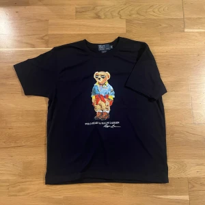 Två Polo Ralph Lauren Bear T-Shirt - Sköna raffe T-shirts. Tröjan är i storlek M. Nyskick! Priset är 499 kr för båda. Hör av er vid frågor eller fler bilder!