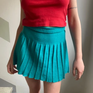 Turkos kortkjol - Säljer en turkos plisserad kortkjol med midjeresår. Köpt vintage i Spanien. Jättebekväm och snygg. Fungerar för flera storlekar. Påminner om havet och karameller.