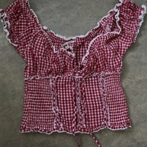 Röd och vit rutig blus/sommartopp (Kimchi Blue Nadia Gingham Shirred  Blouse) - Slutsåld med original pris på 400kr! Supersöt röd och vit rutig blus från Kimchi Blue med volangdetaljer och smockad midja. Blusen har korta ärmar och dekorativa spetskanter. Perfekt för en somrig look.