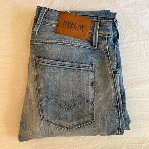 Replay Anbass ljusblå jeans - Säljer ett par Replay Anbass jeans i ljusblå tvätt med slitningar och klassisk femficksdesign. Jeansen har normal passform och är tillverkade i denim med snygga detaljer och läderpatch bak i midjan. Byxorna är i strl w31 L34