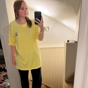Gul t-shirt med broderade kaniner - Säljer en oversized gul t-shirt från märket canda med korta ärmar och en söt broderad detalj av två kaniner på bröstet. T-shirten har rund halsringning och är i mjuk bomull, perfekt för en avslappnad stil. Funkar för alla kön! Den är väldigt lång och jag är 165 cm. Köptes i München i en dyr affär. 