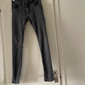 Grå skinny jeans från Diesel  - Säljer ett par grå skinny jeans från Diesel industry Klassisk femficksmodell med dragkedja och knapp i midjan. Snygg tvätt och smal passform som sitter tight hela vägen ner. Storlek 14 år 