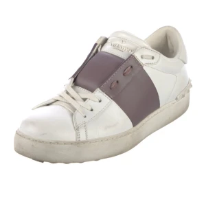 Valentino Open sneakers i vitt skinn med lila detalj - Snygga Valentino Open sneakers i vitt skinn med bred lila rem över mitten och klassiska nitar på hälen. Skorna har snörning och rund tå, perfekt för dig som gillar stilrena men unika sneakers.