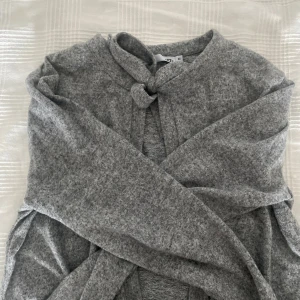 Grå kofta med knyt - Mysig grå kofta med knyt framtill vid halsen. Koftan är långärmad och har en mjuk, stickad känsla som passar perfekt till kyligare dagar. Säljer eftersom att den inte kommer inte användning. Använd fåtal gånger.💞
